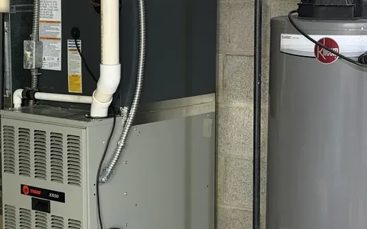 Rheem gas water heater beside a Trane furnace in a basement in Avon, OH